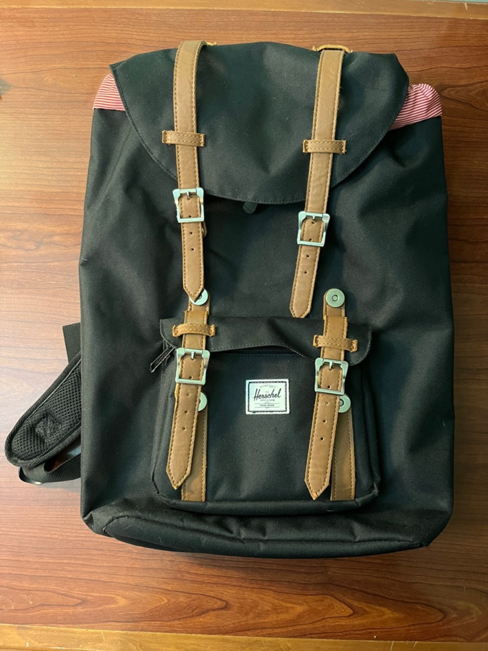 Black Herschel backpack with red and white striped lining.